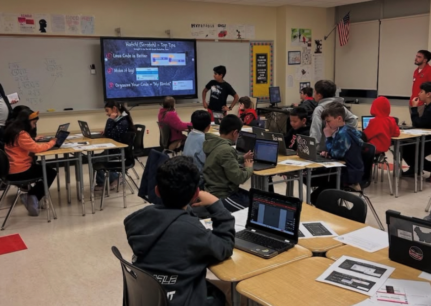 Students participating in Technology and Coding Night workshop with laptops